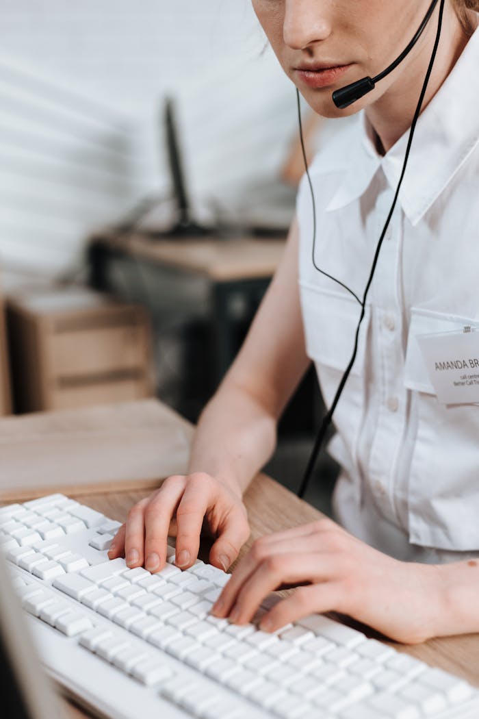 Mastering the First Impression: Your intriguing post title goes here Close-up of a female call center agent typing on a keyboard, wearing a headset in an office setting.