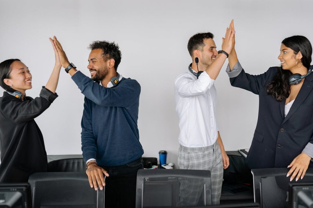 Diverse team of call center agents high-fiving in an office environment showcasing teamwork and collaboration.